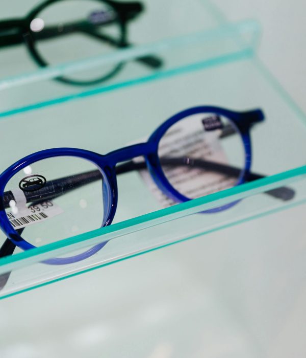 pexels-photo-5202050-5202050-1 Modern blue eyeglasses showcased in a glass display case, perfect for fashion and optics themes.